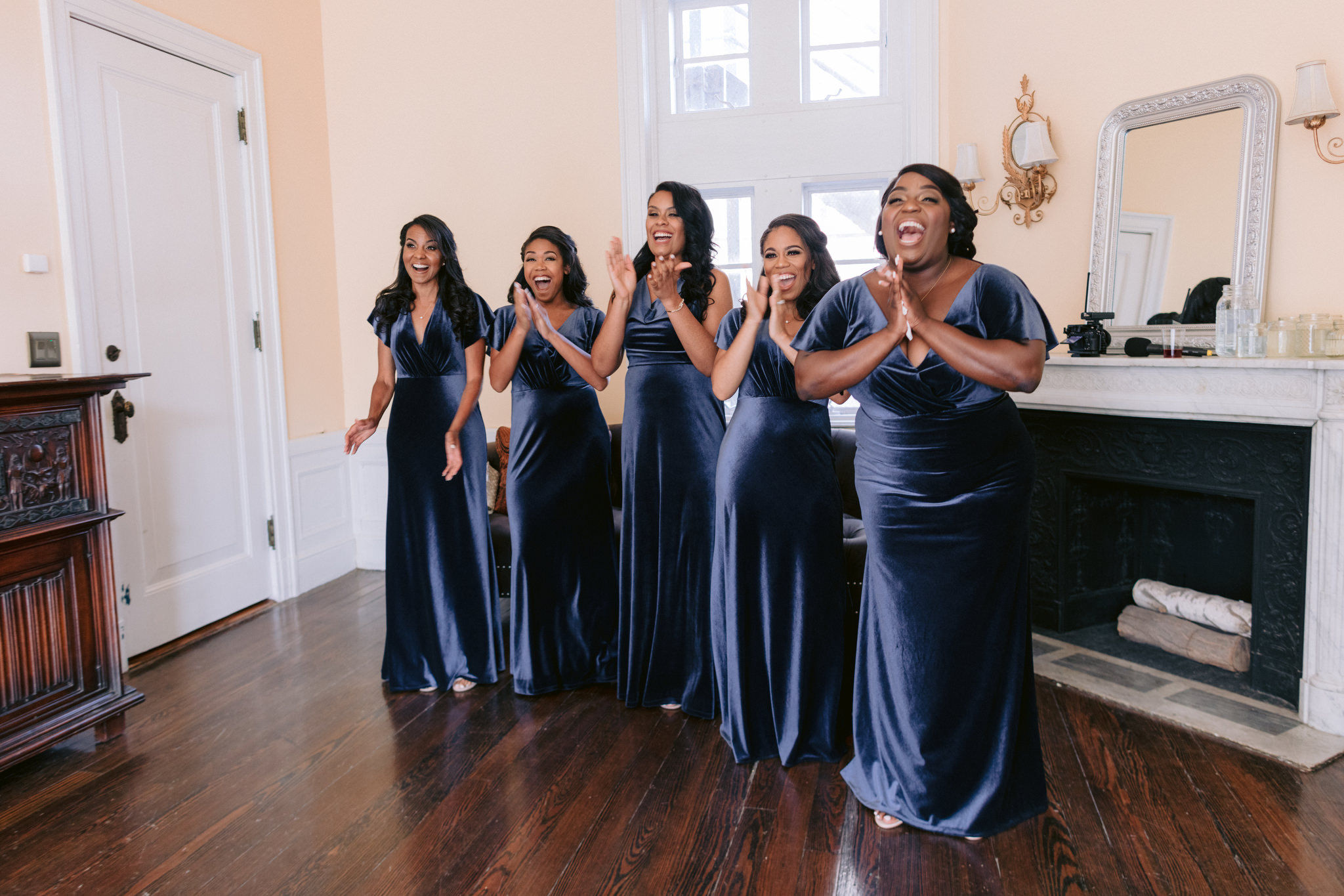 Bridesmaids smiling and clapping wearing navy blue floor length dresses