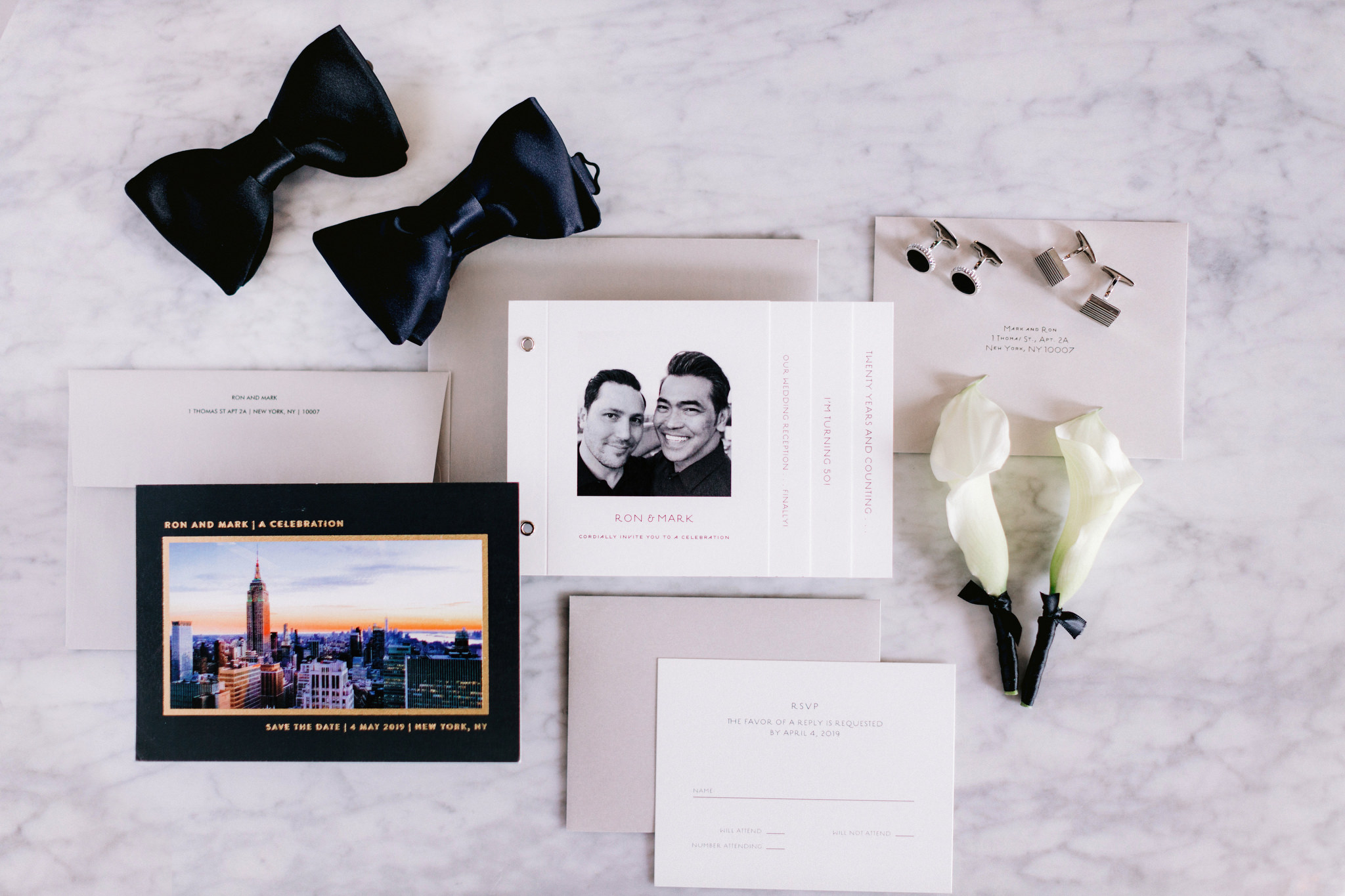 Wedding invitation for same sex wedding on table with bow ties boutonnieres and cuff links