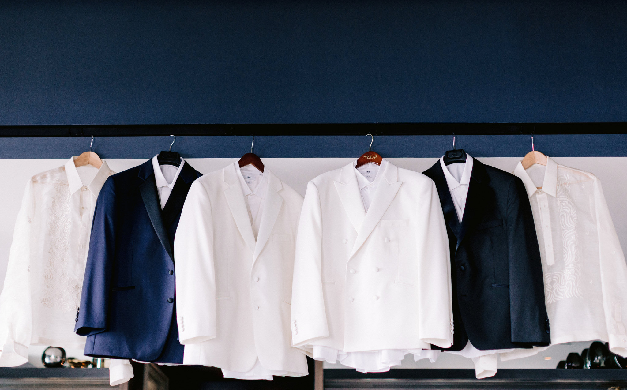 White and blue suit jackets hung up in a row before wedding