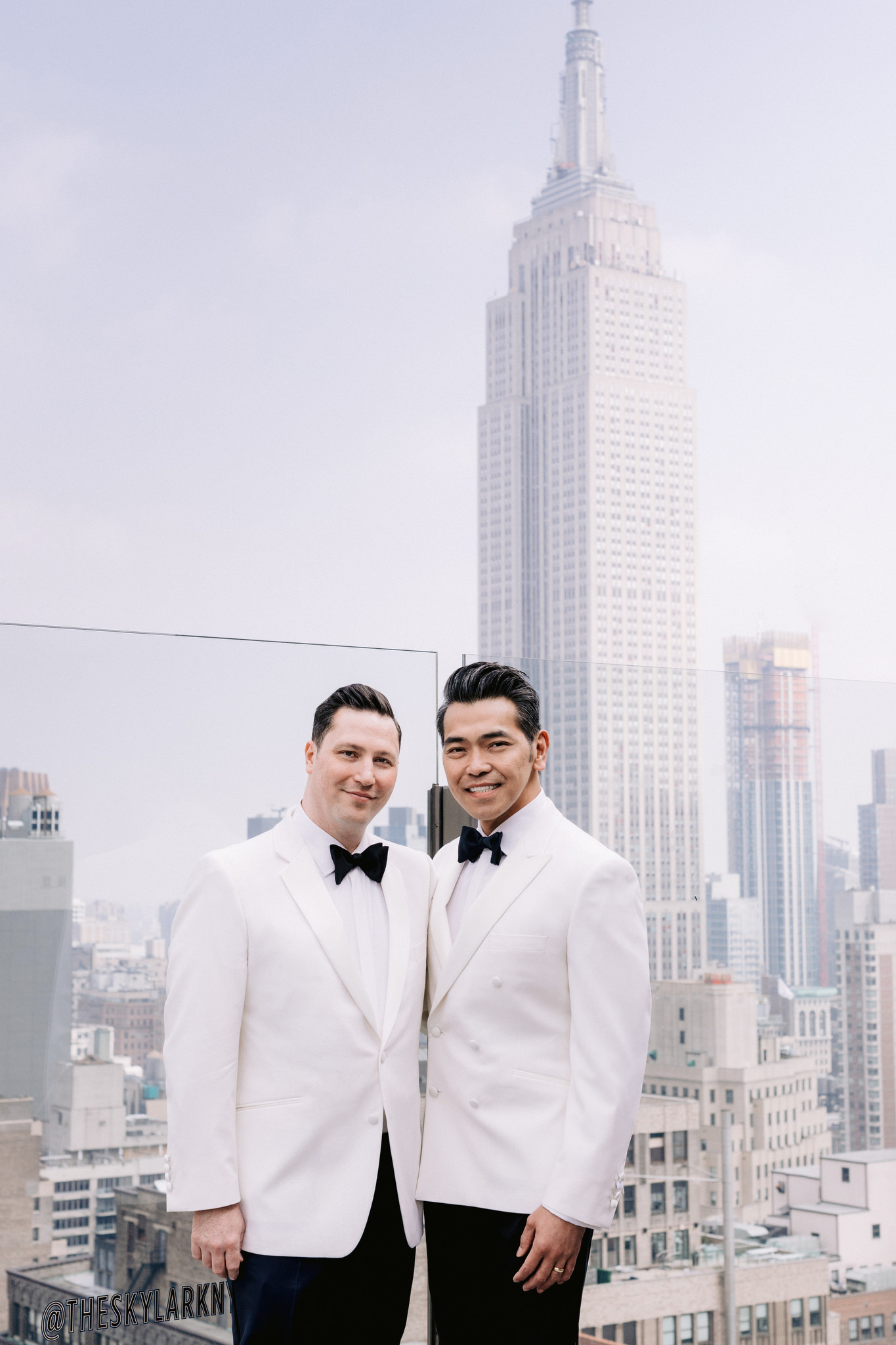 Same sex male couple in white suits on wedding day with Empire State Building in background