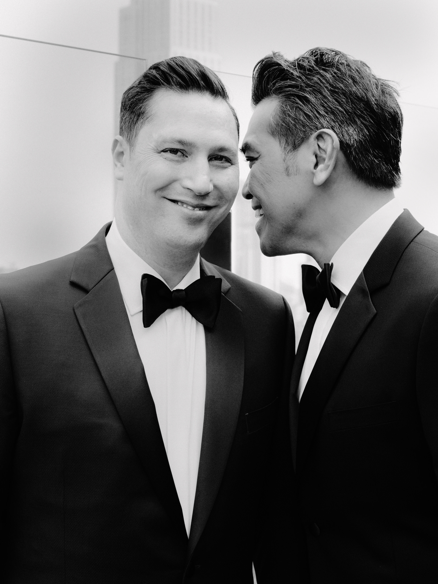 Same sex male couple smiling at each other wearing suits on wedding day
