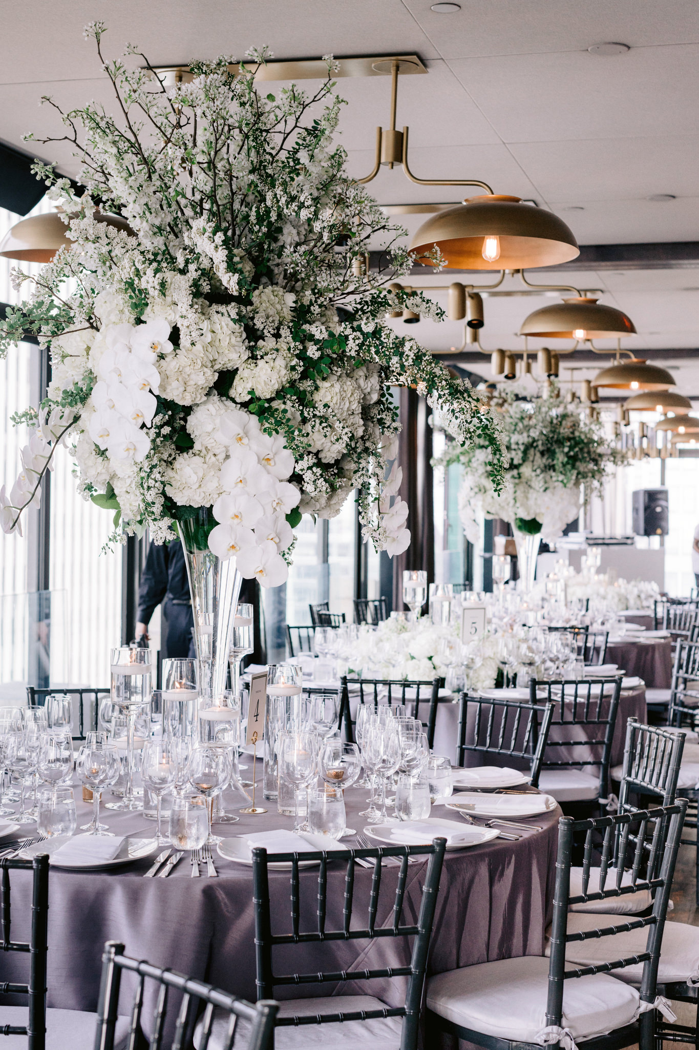 View of dining room with tall white floral centerpieces at Skylark New York Wedding