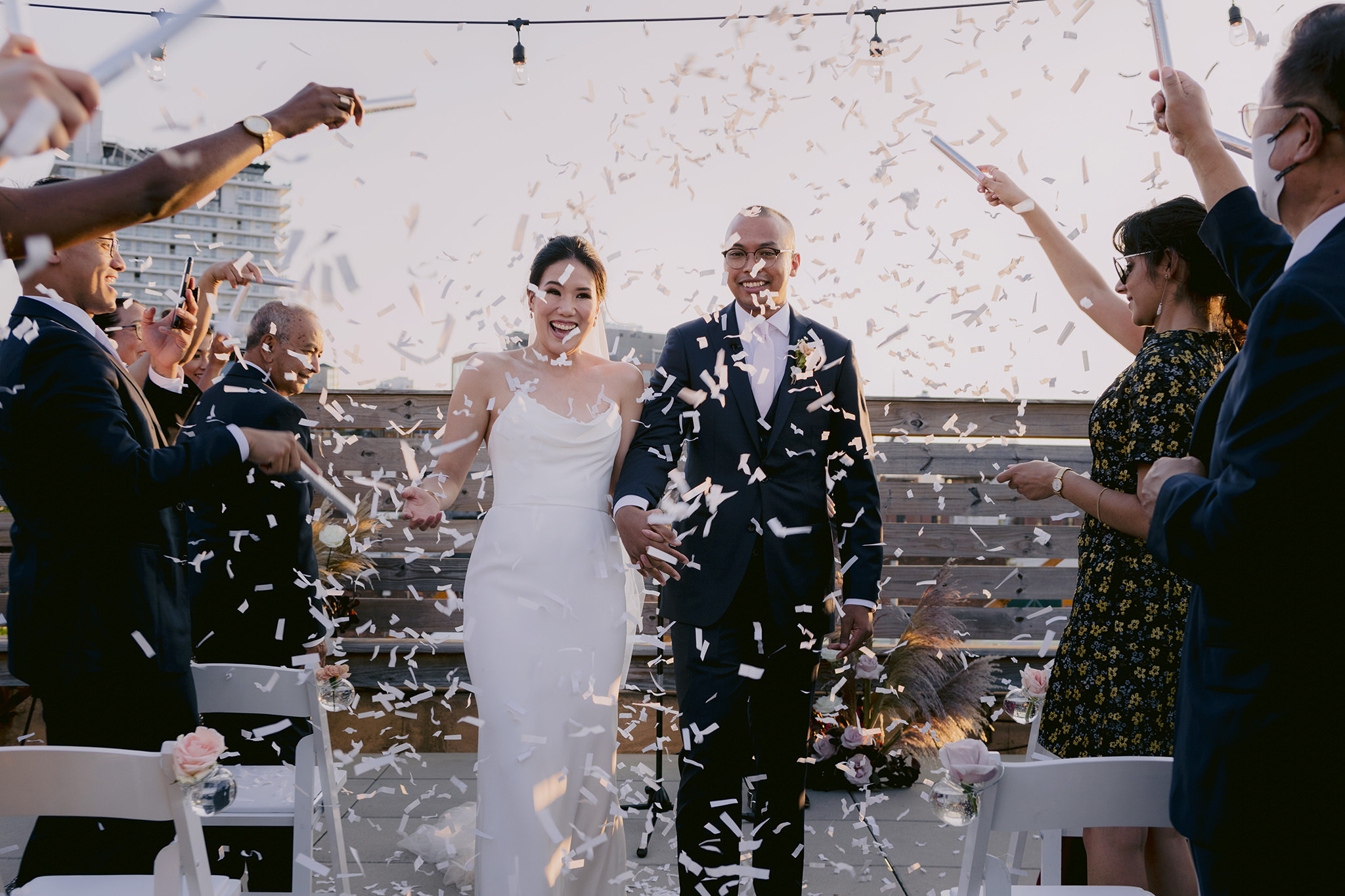 Wedding guests throw confetti as bride and groom walk down the aisle