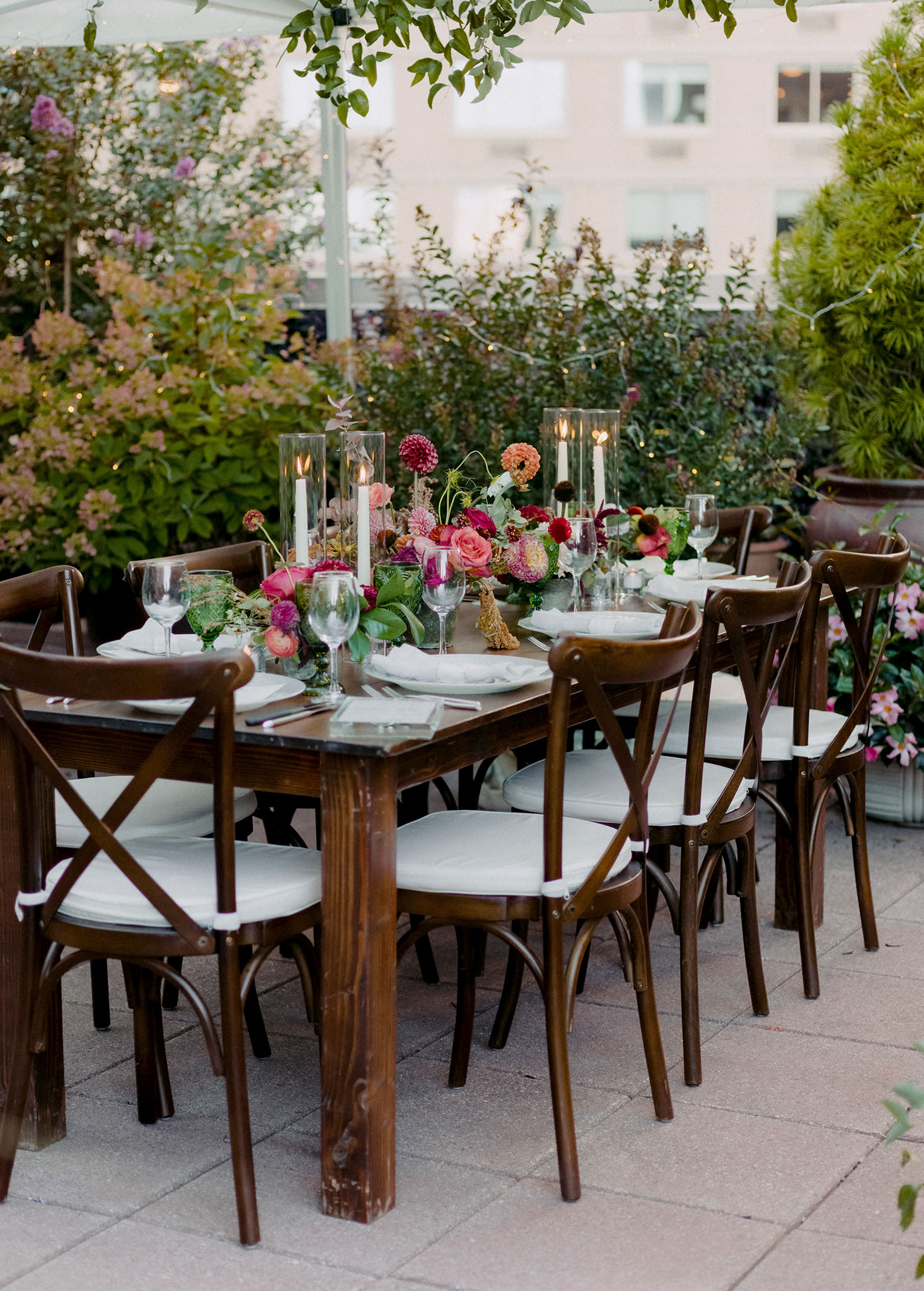 Red, pink, and orange floral center pieces on a rooftop patio