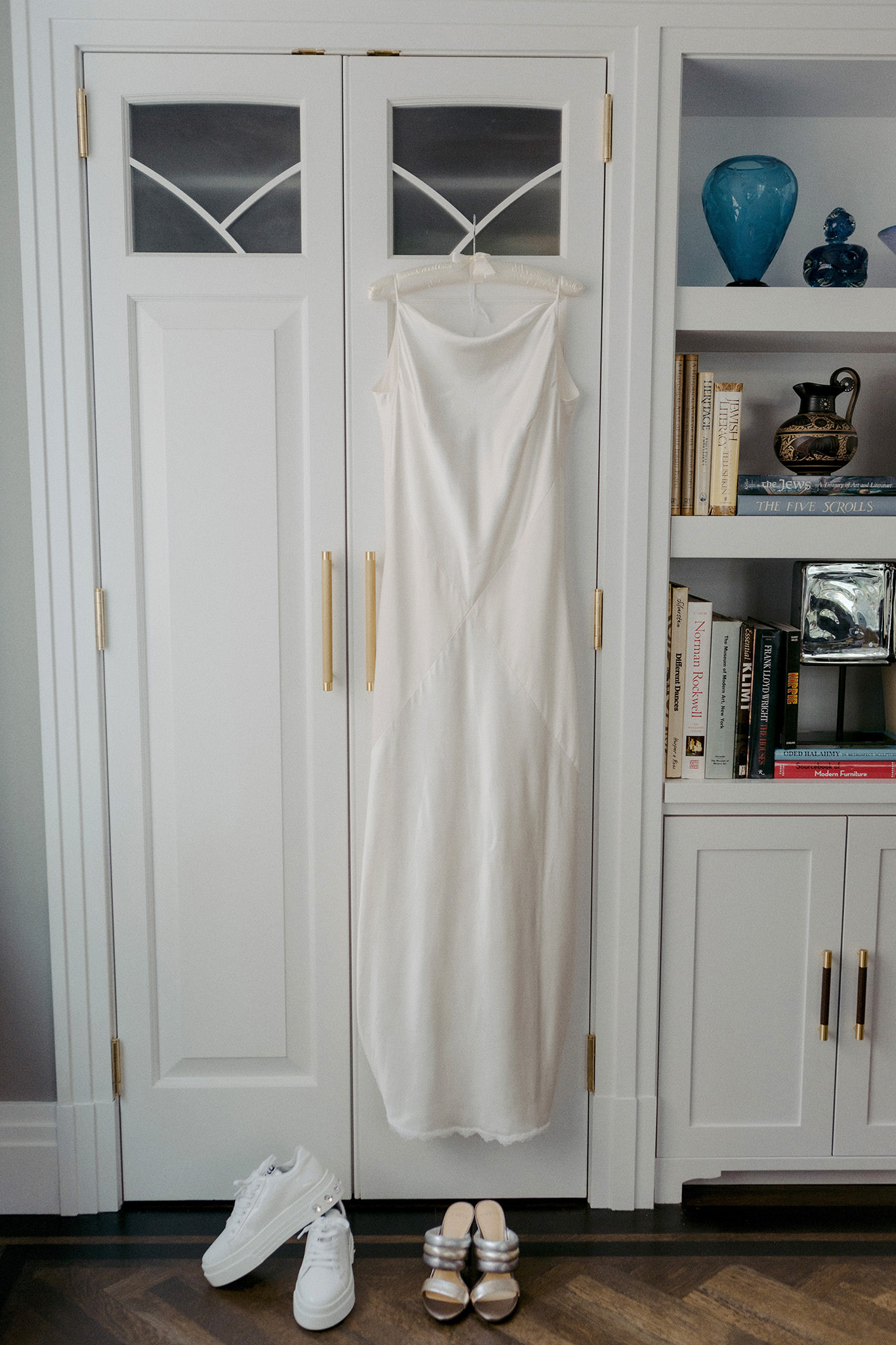 Bridal wedding details on wedding day. White wedding dress hanging from a hanger in Manhattan living room.