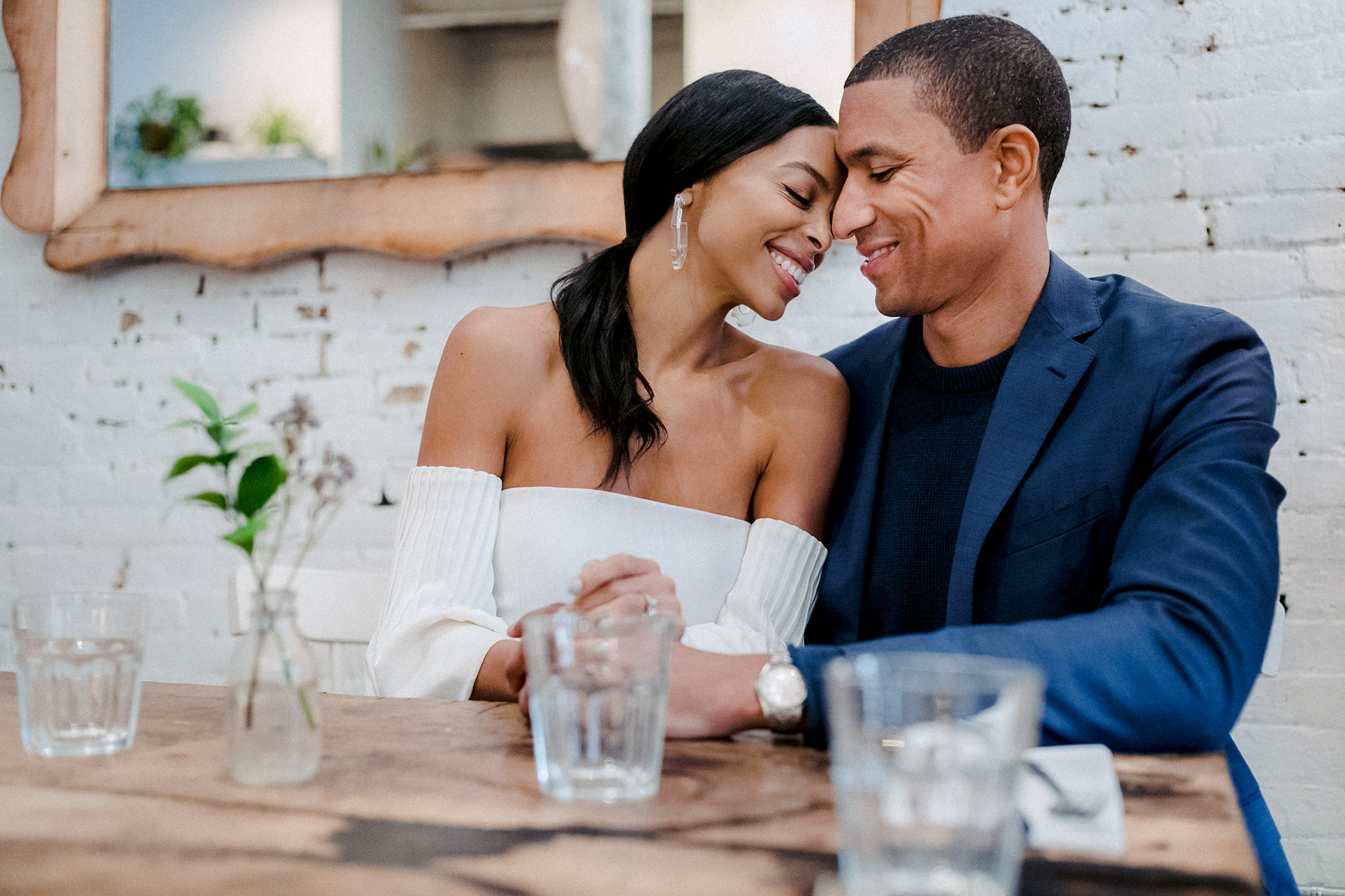 Bride and groom leaning into one another at a restaurant during their engagement session