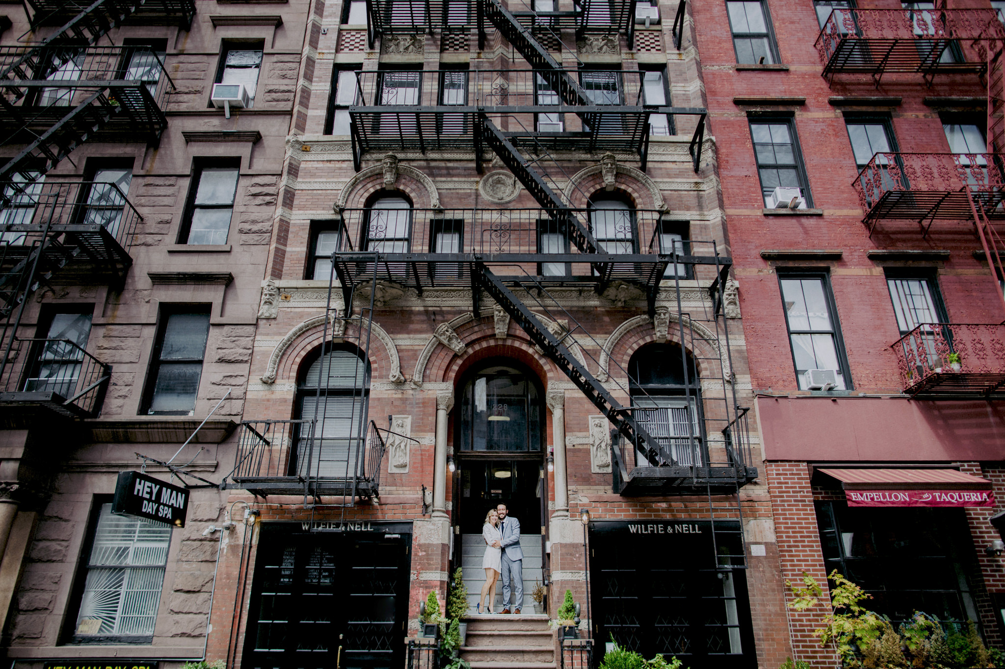 Elopement couple standing on the steps of a brownstone in Manhattan holding each other.