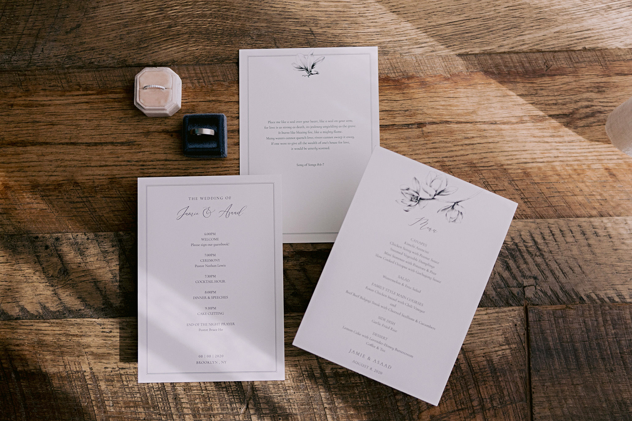 Wedding invitations and wedding bands placed on a wooden table top.