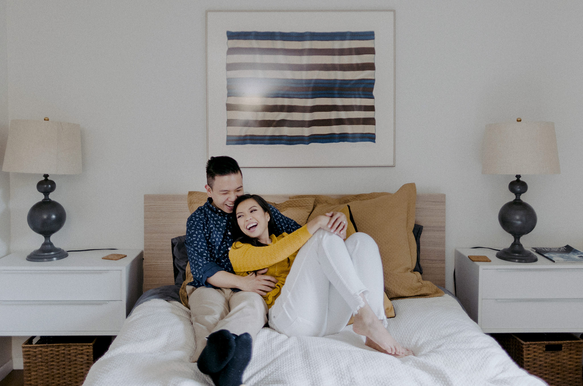 Bride to be and fiance snuggling on their bed in at indoor engagement session