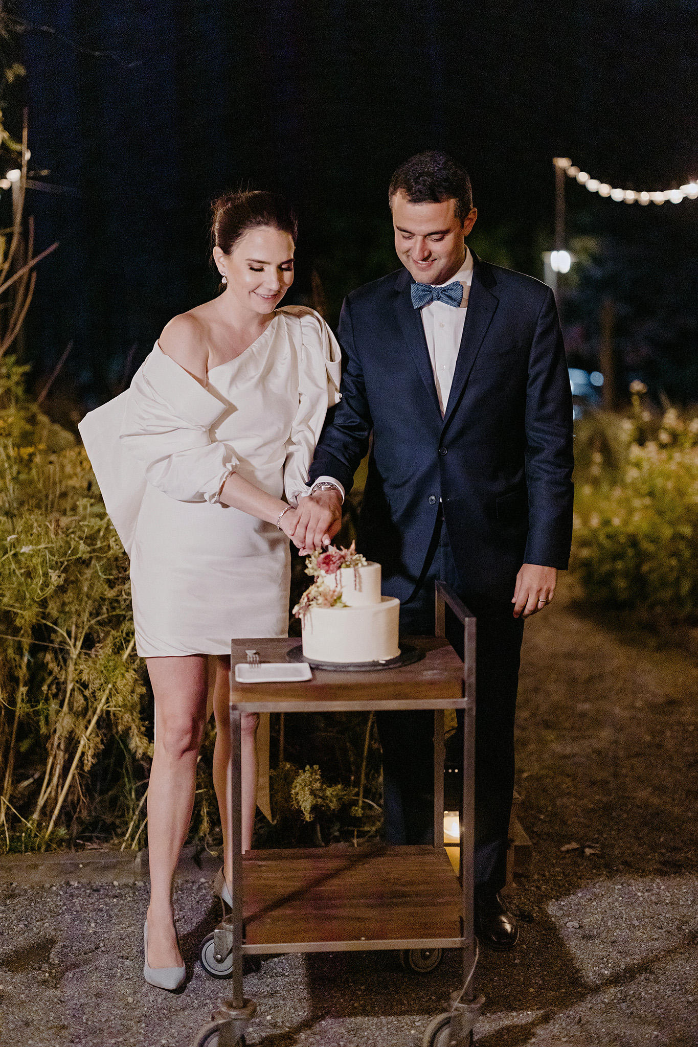 Bride and groom cut their cake at night at Blue Hill at Stone Barns garden.