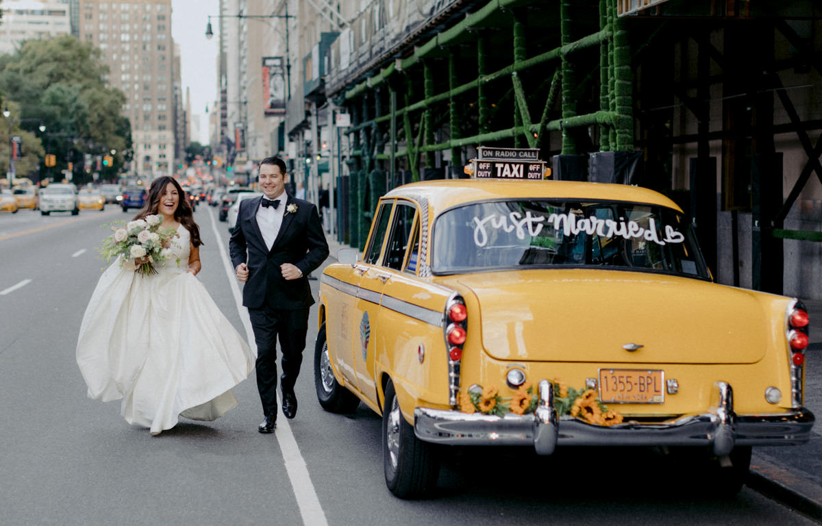 Bride and groom walking in the streets of New York City with a vintage taxi