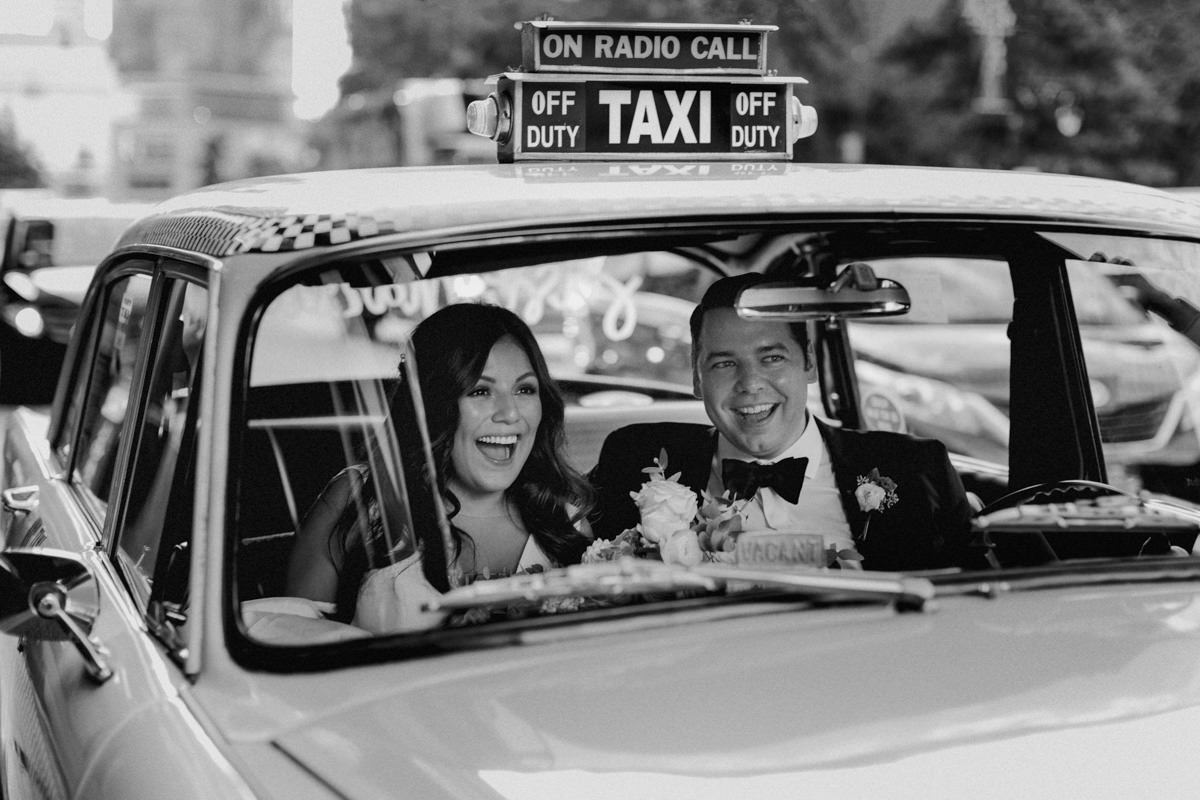 Bride and groom riding in a vintage nyc taxi.