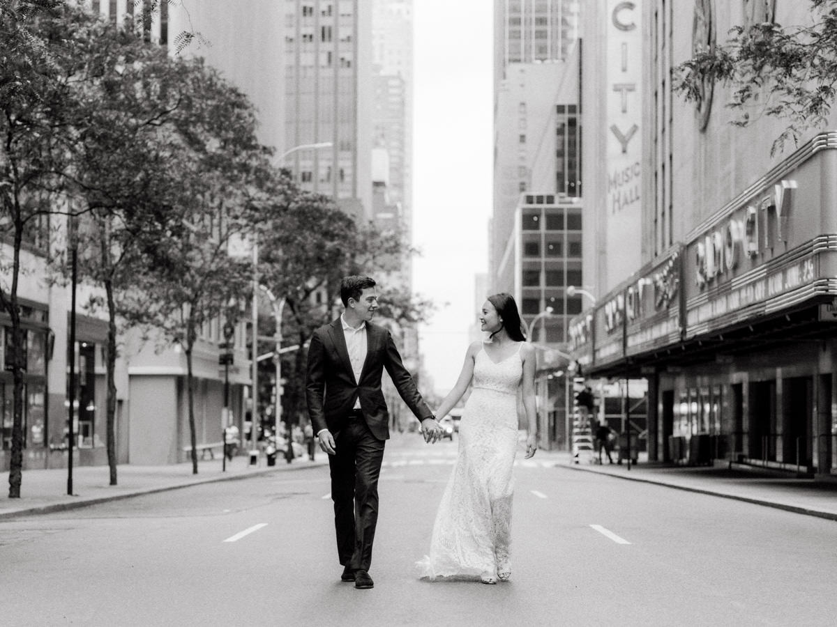 Bride and groom hold hands in the outside of Radio City Music Hall at 30 Rockefeller Plaza