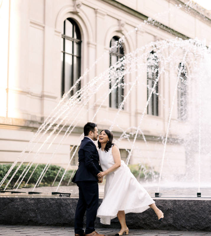 Husband and wife kissing in front of a fountain for their wedding photos