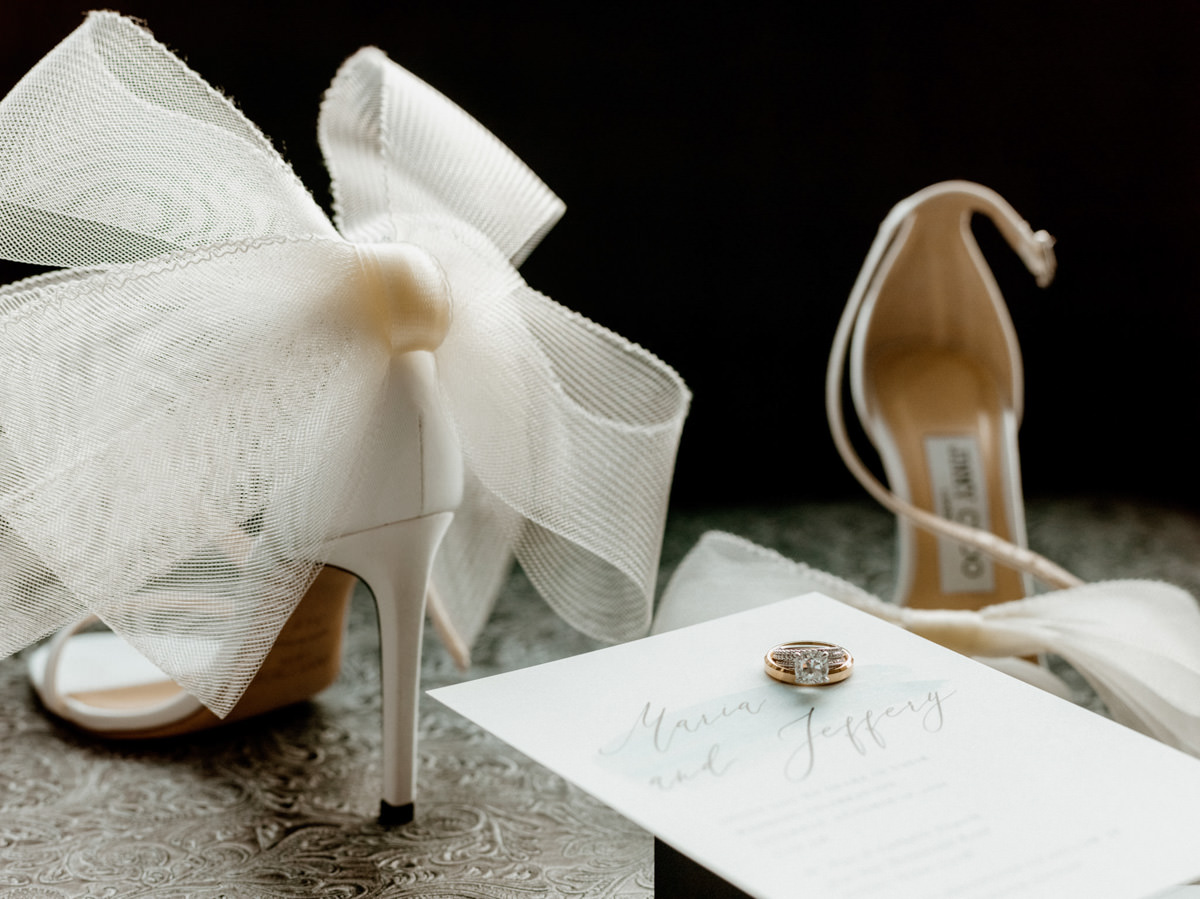 Jimmy Choo heels and wedding bands placed on a wedding invitation