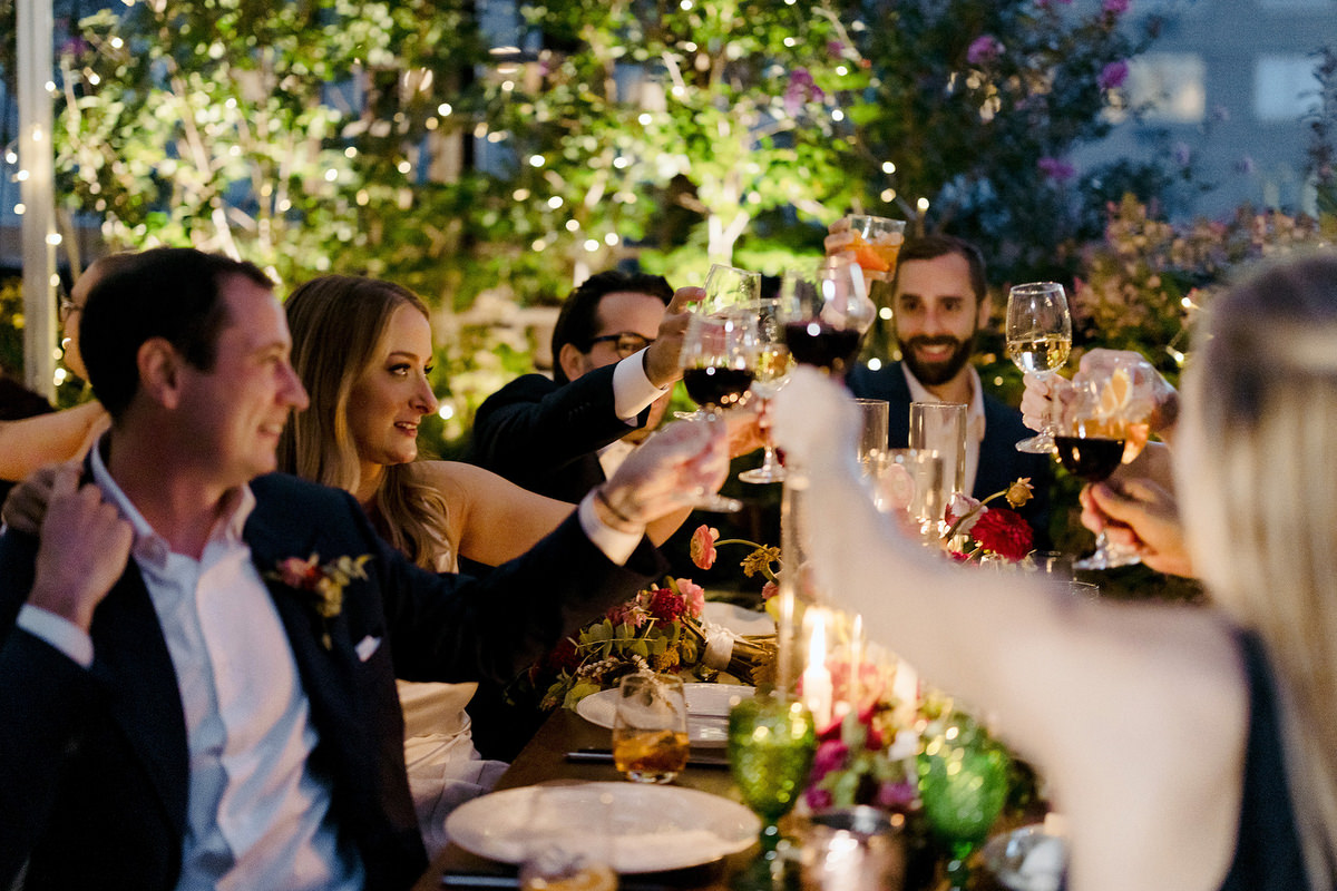 Wedding guests cheers their wine glasses over candlelight 