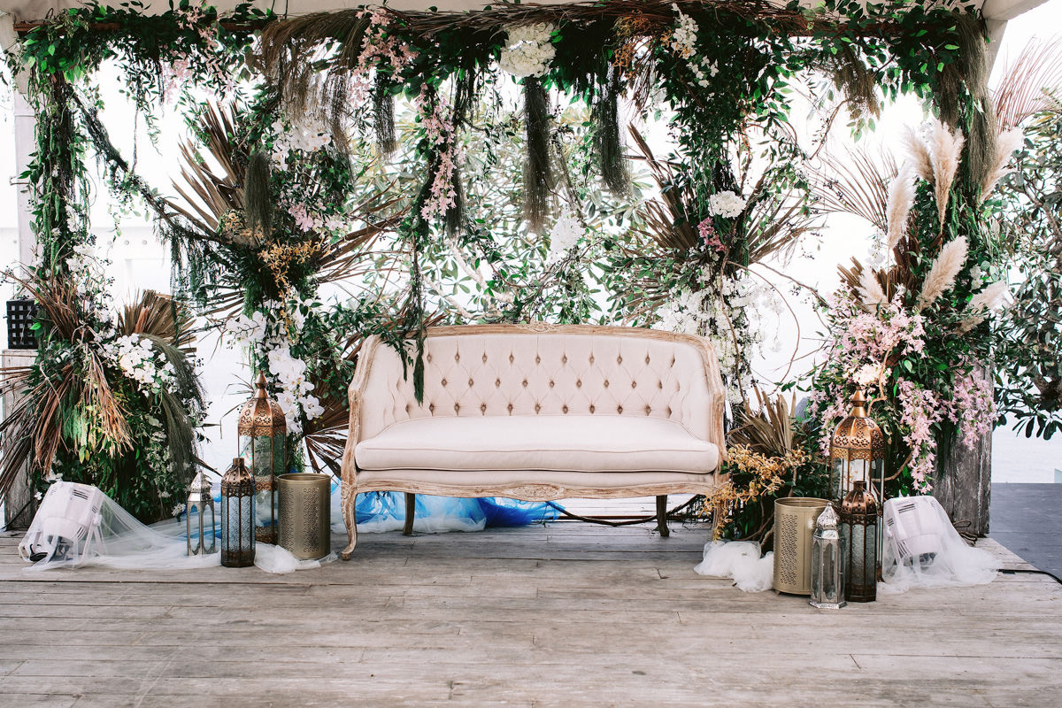 A white couch surrounded by greenery, executed by a wedding planner