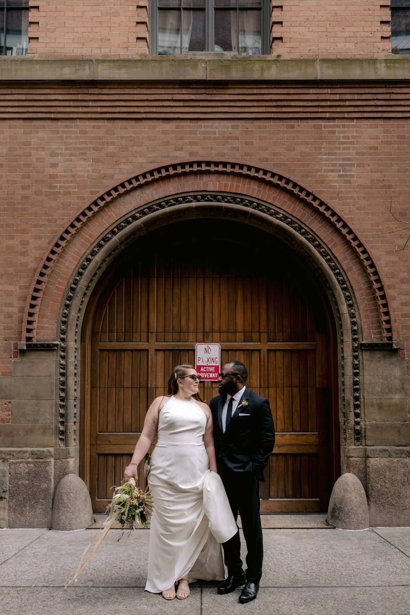 Wedding photographer Jenny Fu snaps a shot of a biracial bride and groom in front of a wooden doorway