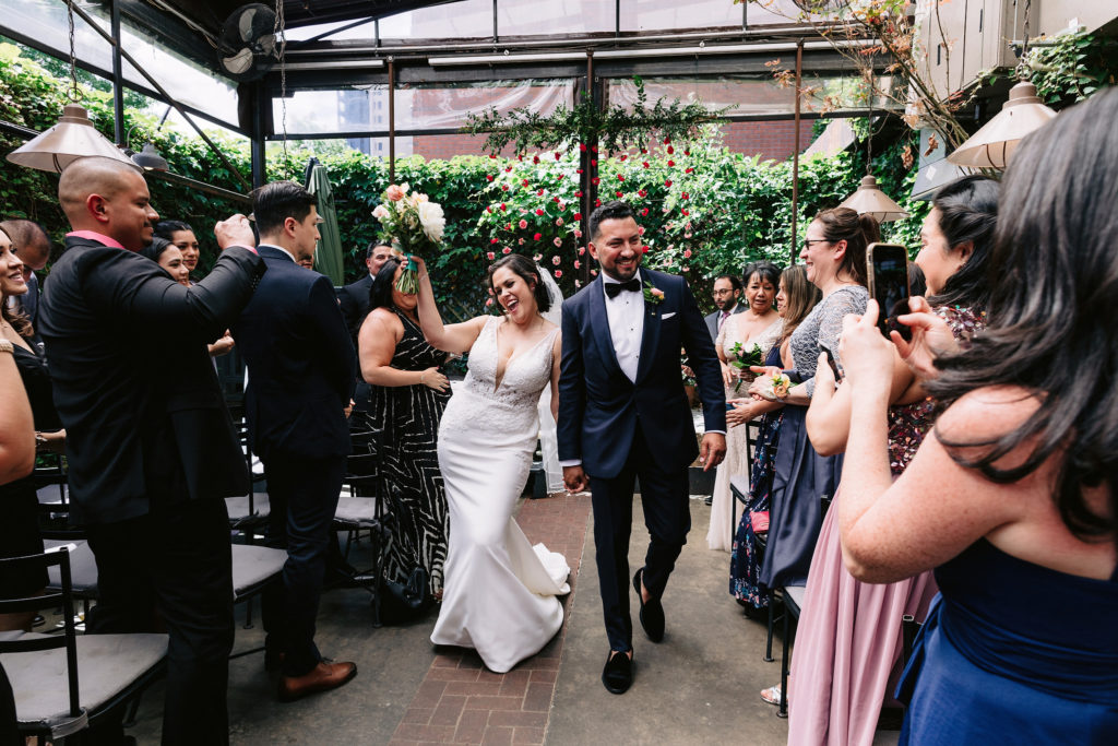 A wedding photographer captures the bride and groom walking down the ailse