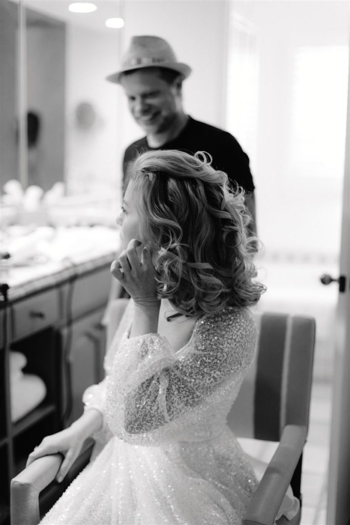 A bride puts on her earrings in a dressing room at-home