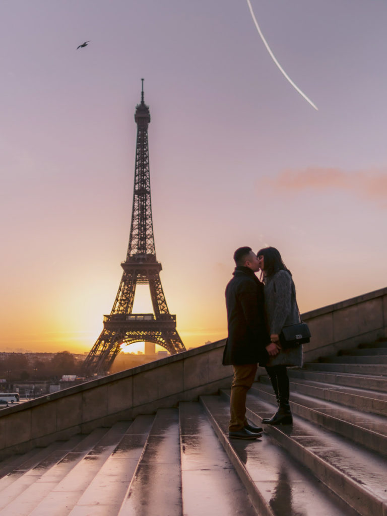 Man and woman kiss in front of the Eiffel Tower