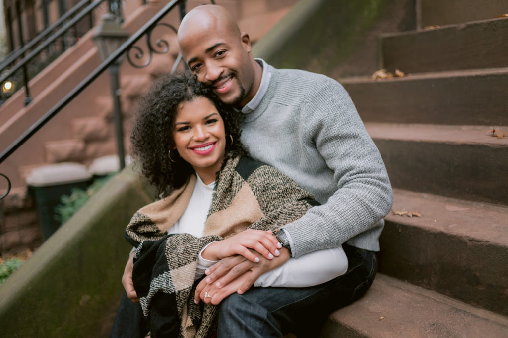 A bi-racial couple sits on a front stoop in New York City