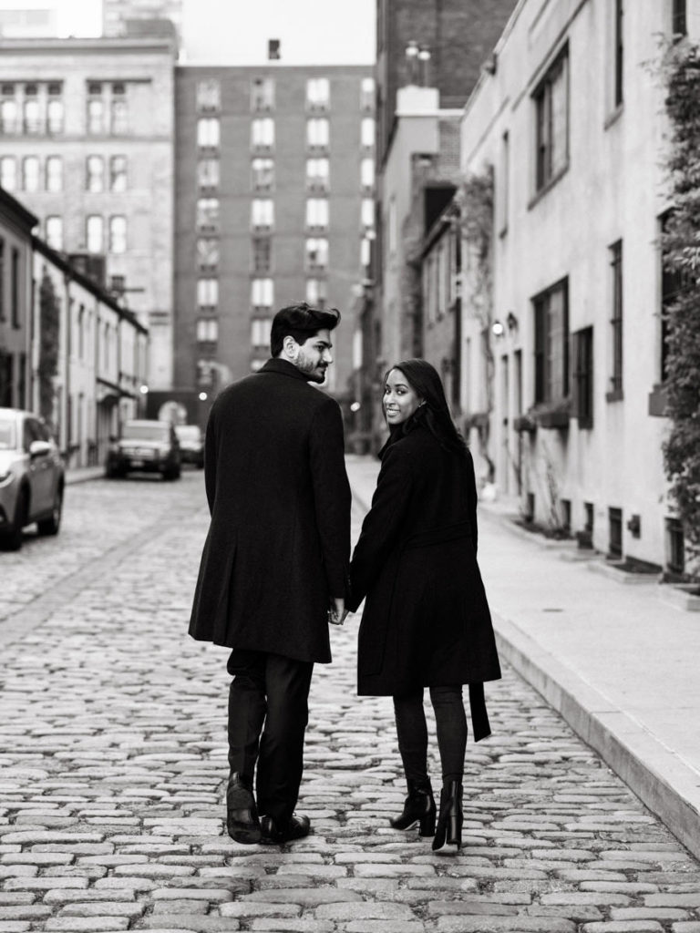 Man and woman walking through the streets of New York City for their engagement photos