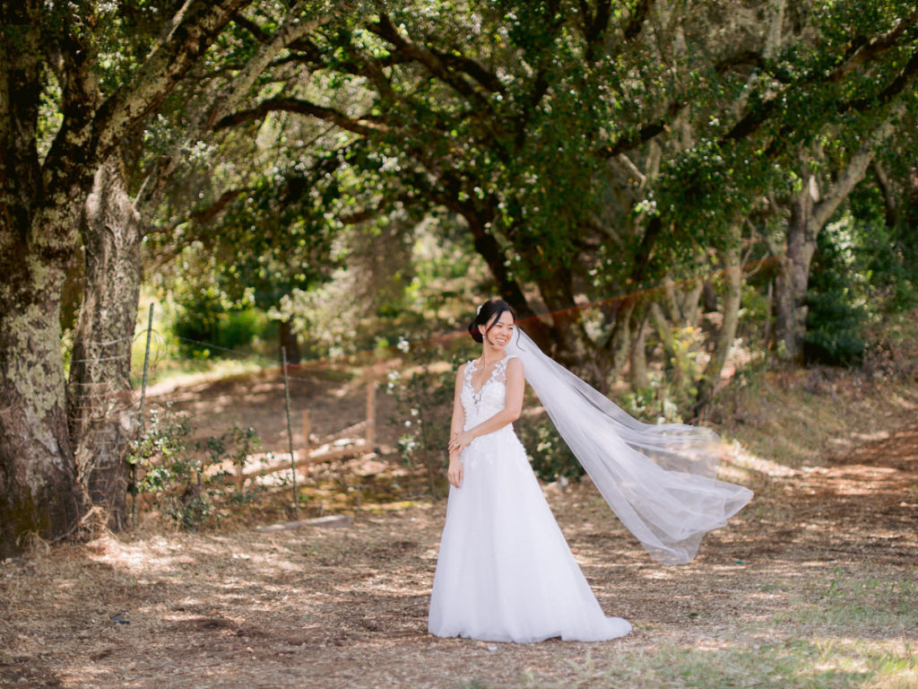Bride in her wedding dress with the veil blowing in the wind with her wedding photographer