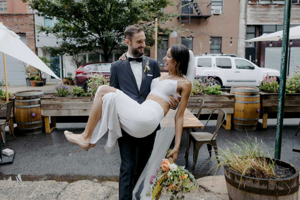 Groom carries his bride into their wedding venue, the Brooklyn Winery