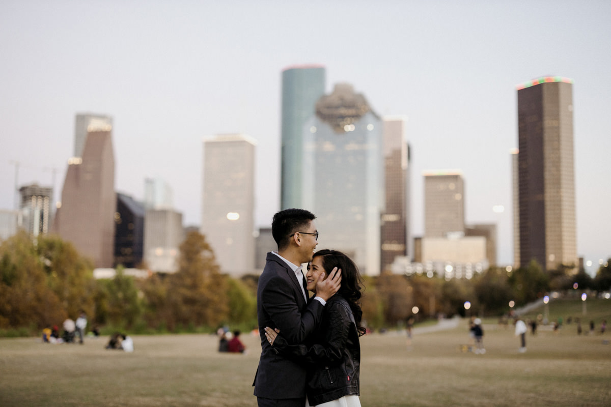 A young couple holds each other in a park in Houston, Texas while reminiscing about their proposal story. 