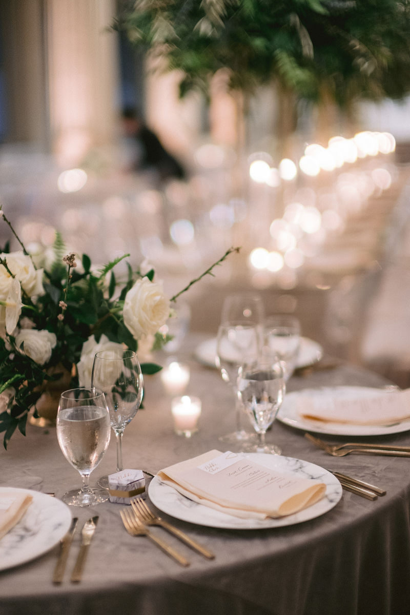 A gold and white table setting at a wedding reception