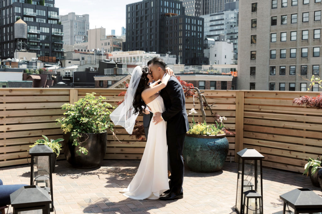 A man and woman kissing on a rooftop in New York City on their wedding day