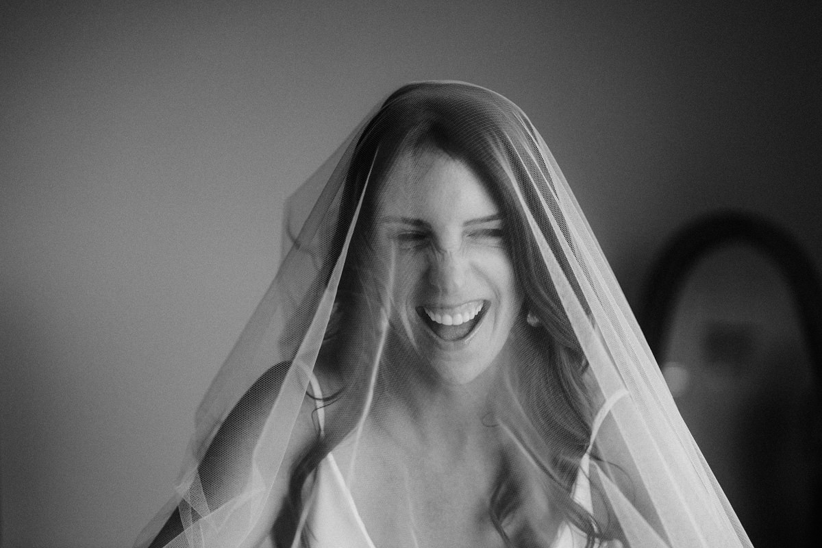A bride laughs with her veil over her head