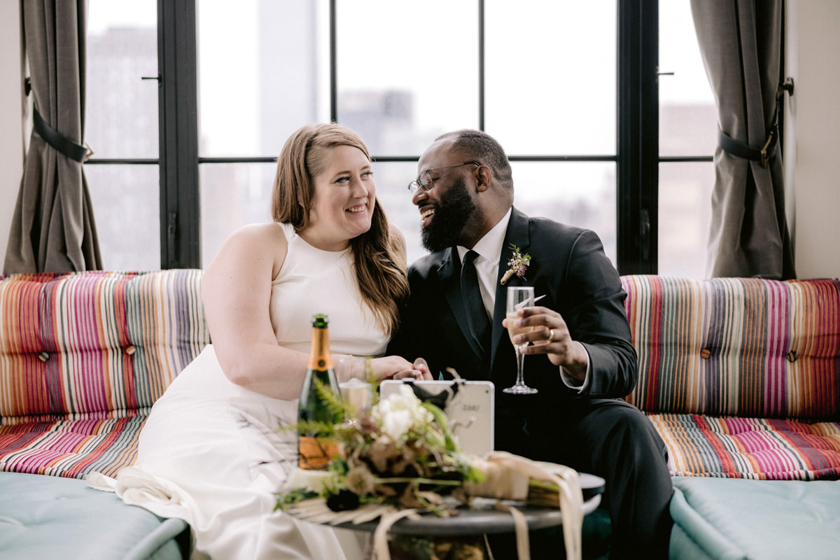 A bride looks into her grooms eyes and drinks a glass of champagne