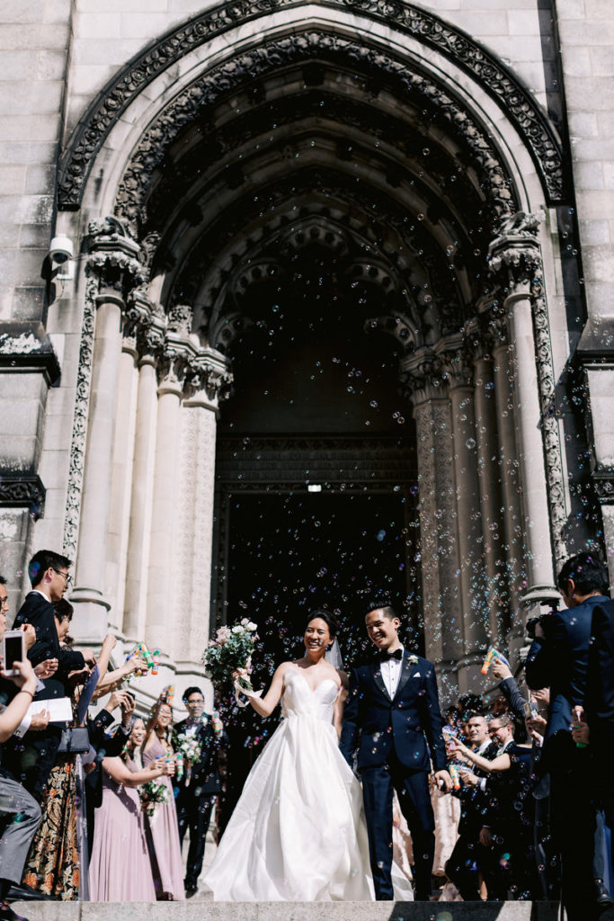 Newlyweds walk out of their church wedding into a sea of bubbles