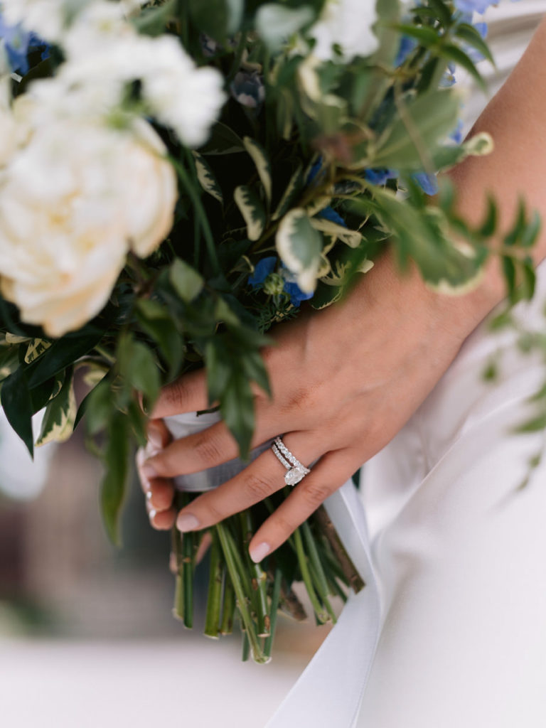 Hands holding a white and blue bridal bouquet