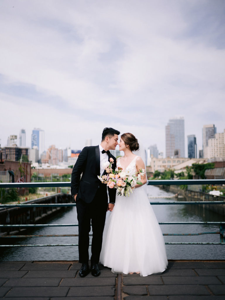 Groom and bride holding hands and kissing on a bridge