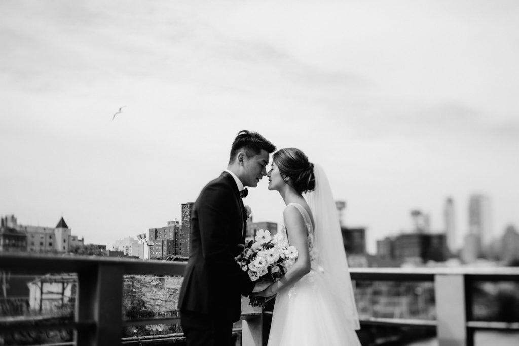 Asian-American bride and groom kiss on a rooftop in New York
