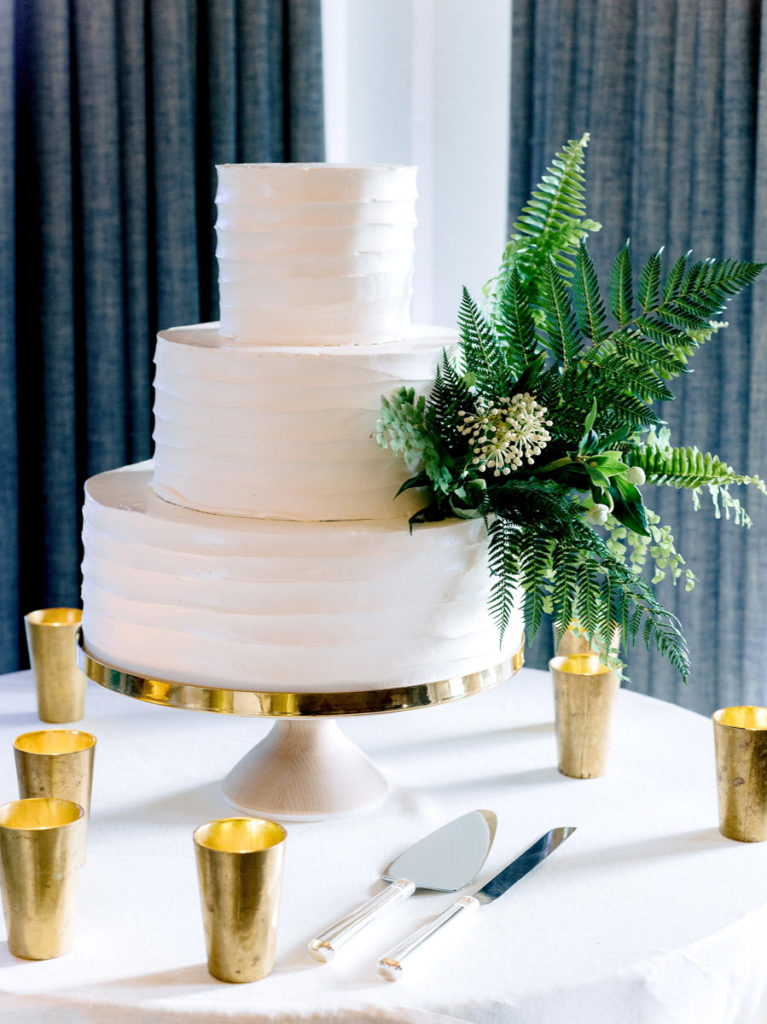 A white wedding cake with ferns and foliage