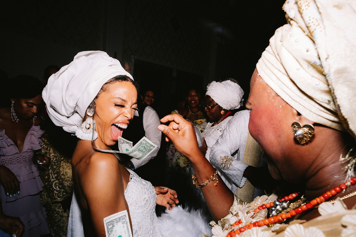 The guests are sticking money in the bride's dress during the money dance at a wedding in NYC. Image by Jenny Fu Studio