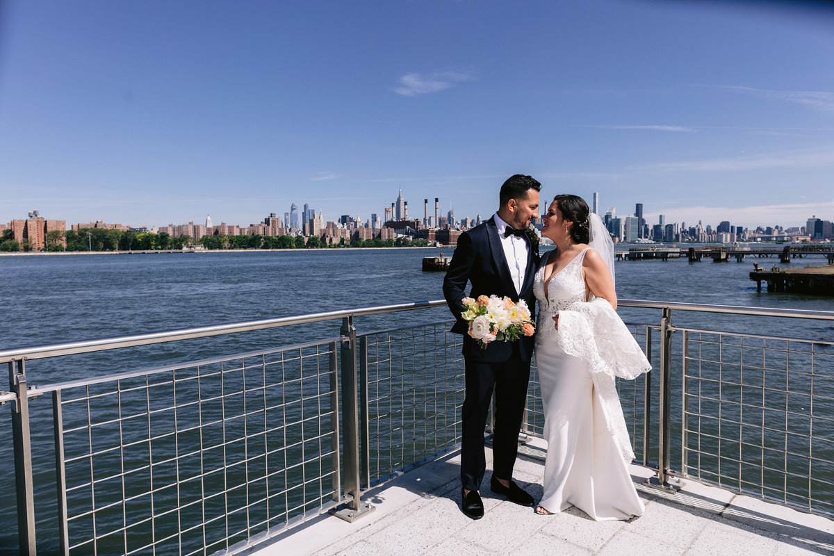 The bride and groom are happily staring at each other, overlooking the ocean. Image by Jenny Fu Best wedding photographers in NYC