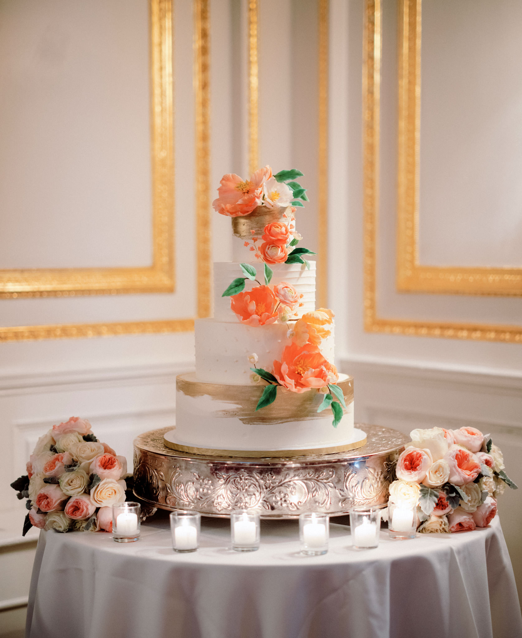 A beautiful, 4-layered, white wedding cake with peach candy flower design. Image by wedding photographer Jenny Fu