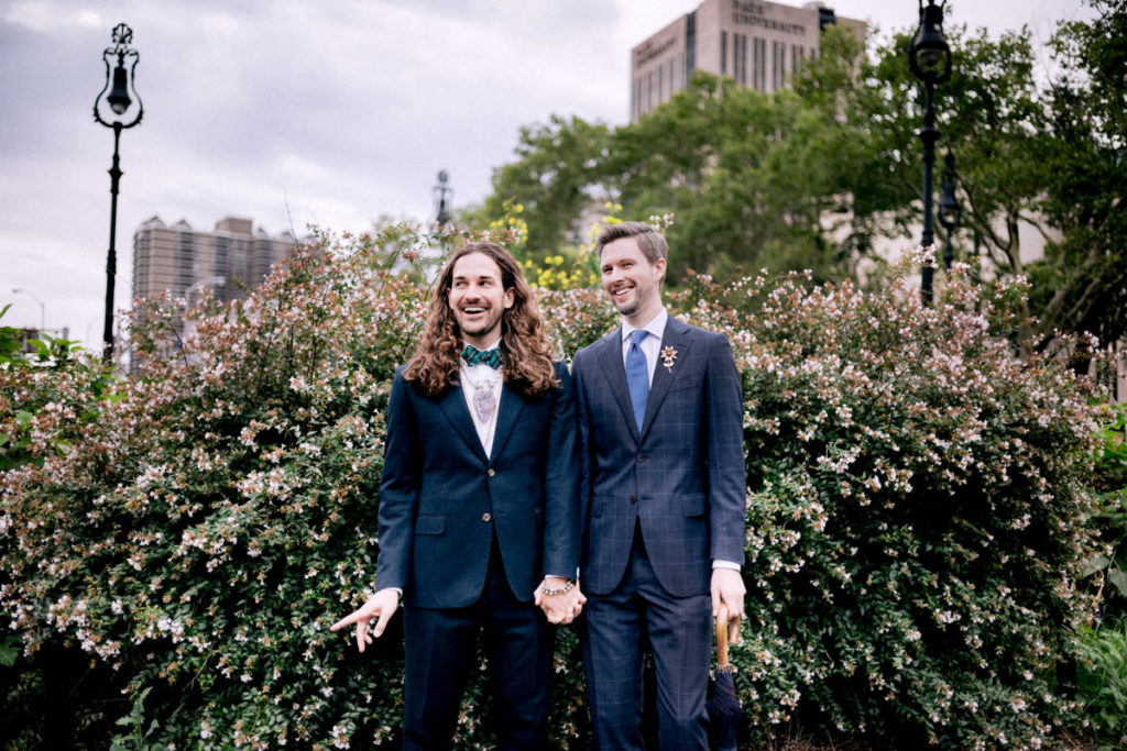 A queer couple in Central Park on their wedding day holding hands