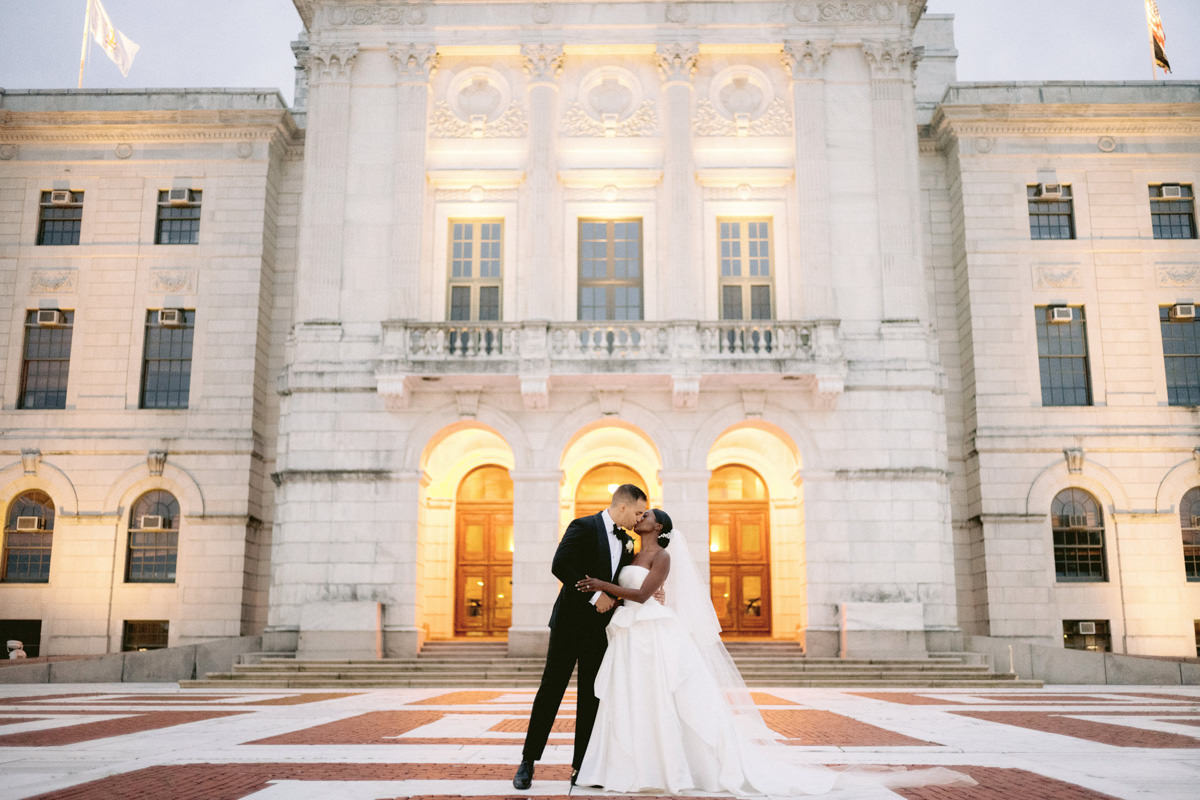 The bride and the groom are kissing in front of a beautiful chateau. Traditional style photography by Jenny Fu Studio