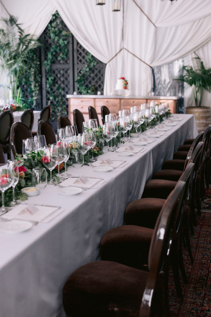 A table with flowers and greenery set up for the pre-wedding rehearsal dinner