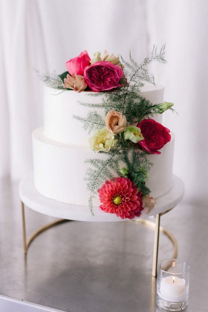 A white cake with pink flowers for the pre-wedding rehearsal dinner