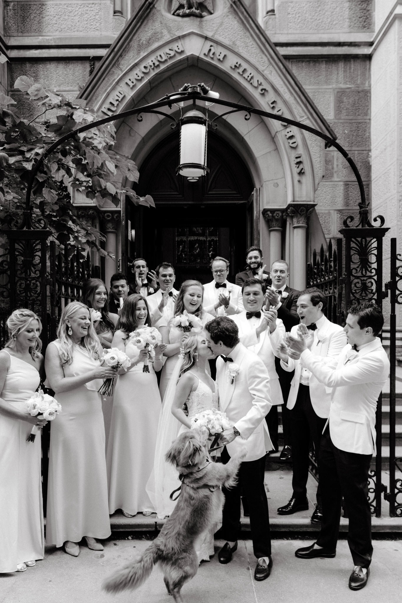 A dog jumps at a bride and groom kissing outside of a New York City wedding venue