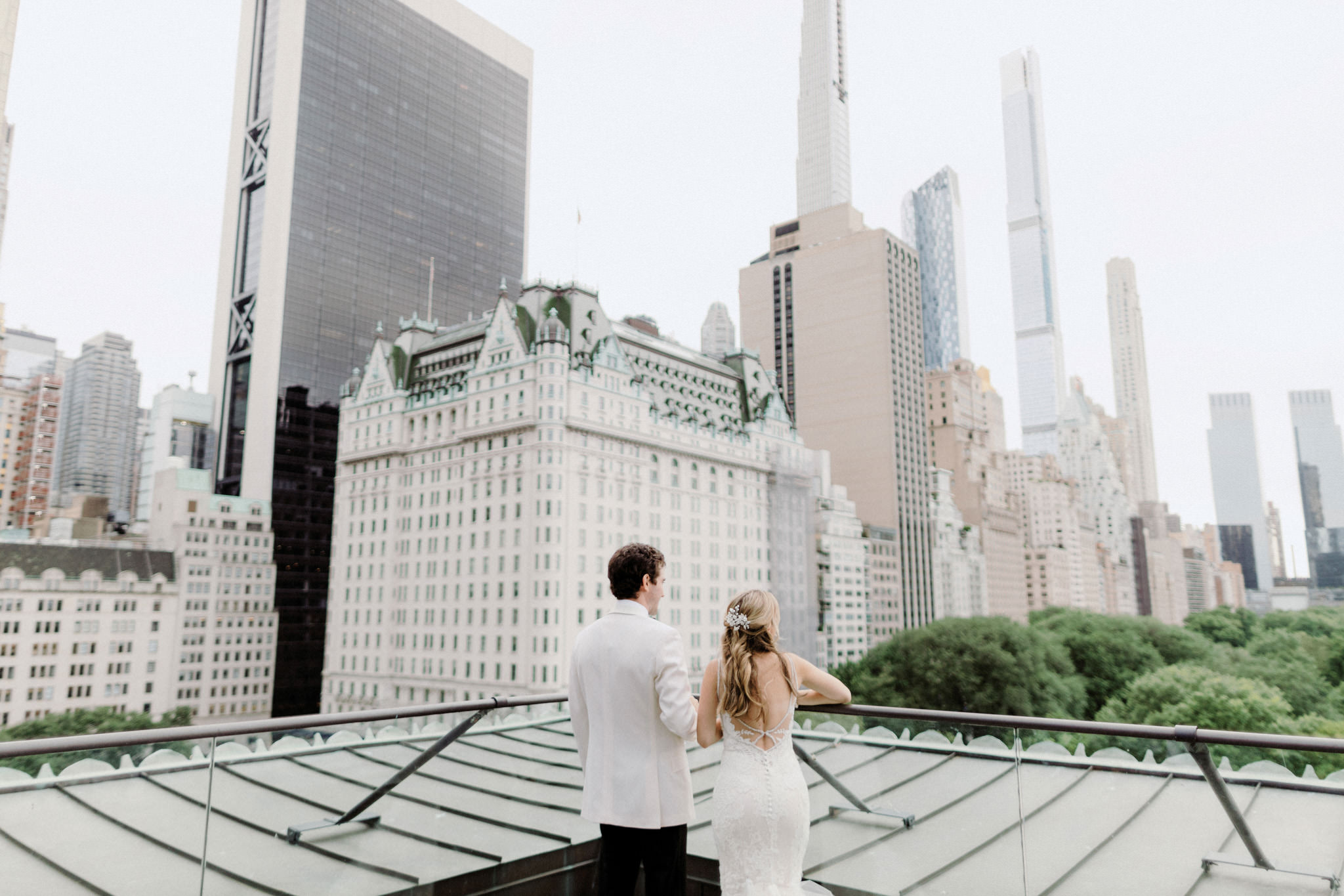 A wedding photographer takes pictures of a bride and groom on a rooftop in New York City