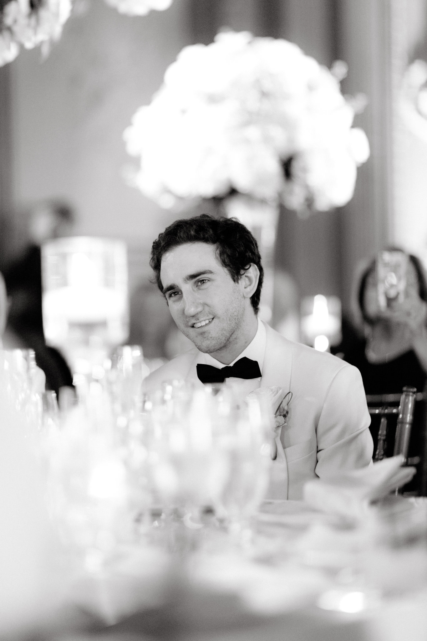 A man in a white tuxedo smiles