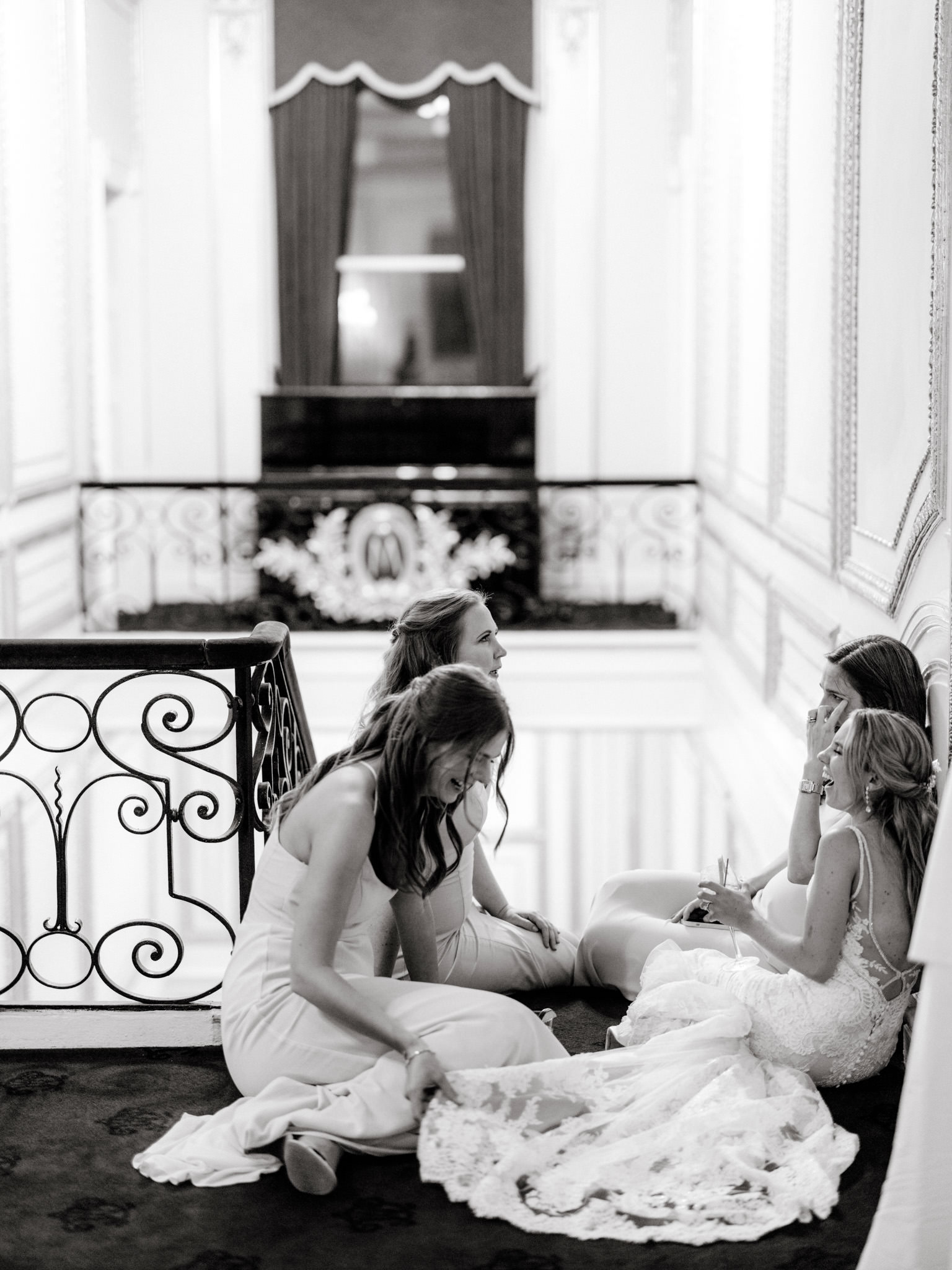 The bride is happily chatting with her bridesmaids while slumped on the top of the staircase. Image by Jenny Fu Studio